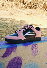 Pink and black sneaker with a white logo on a colorful concrete surface.